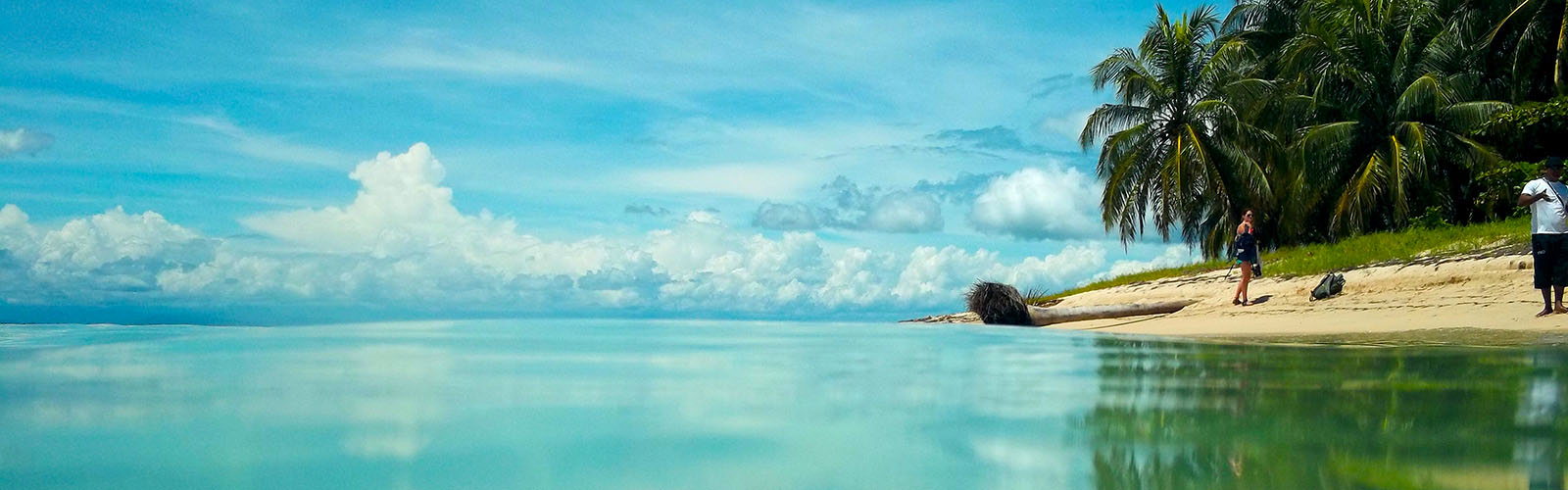 Water extending to a cloud-filled horizon, with a beach close and on the right.